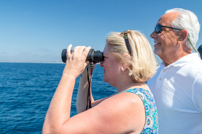 A husband and wife whale watching with binoculars