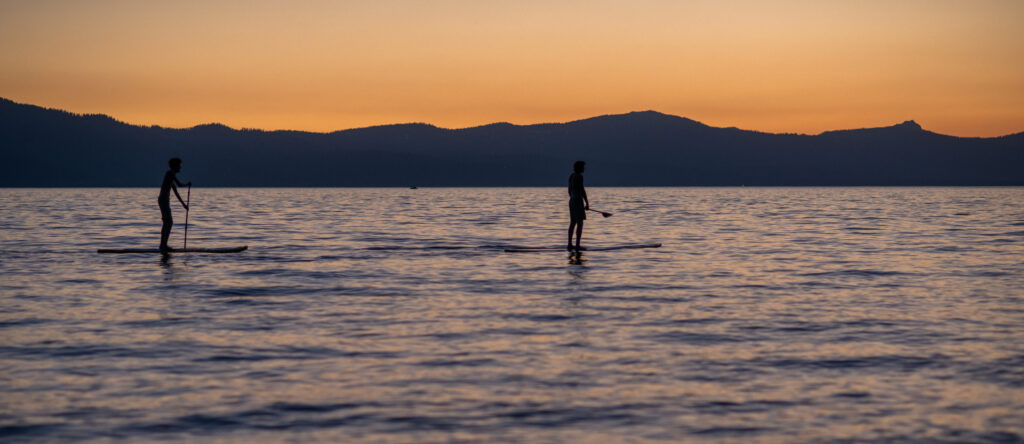 Two people paddleboarding at sunset